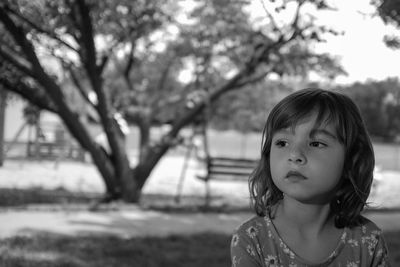 Close-up of cute girl looking away while sitting at park