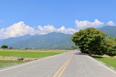 Empty road by mountains against sky