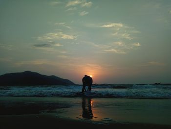 Silhouette man at beach against sky during sunset