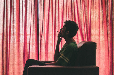 Side view of woman sitting on chair at home