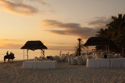 People at beach against sky during sunset