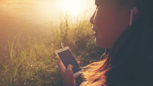 Side view of man using mobile phone at sunset