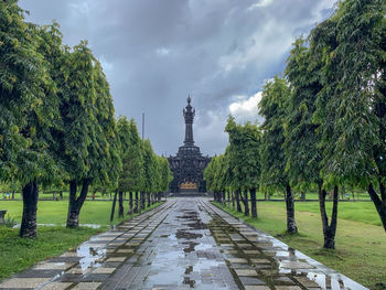 Footpath amidst trees against sky
