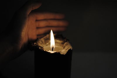 Close-up of hand by burning candle