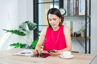 Young woman holding coffee cup on table