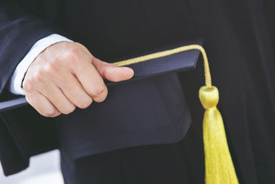 Midsection of student holding mortarboard