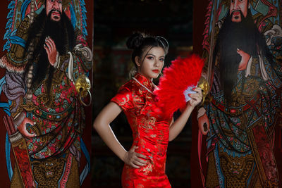 Portrait of beautiful model in red traditional clothing standing by door