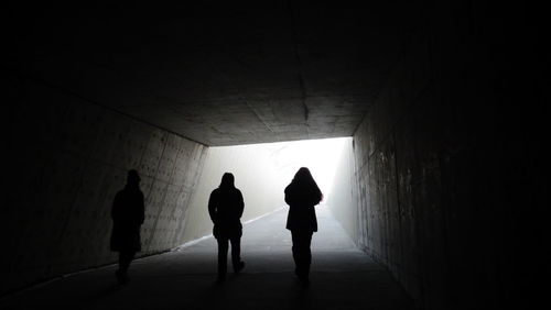 Silhouette people walking in tunnel
