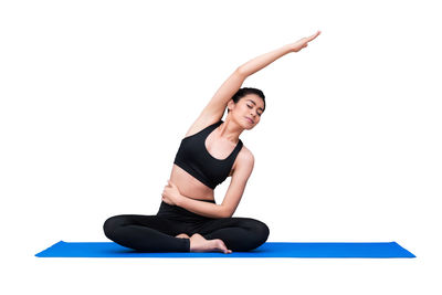 Full length of woman with arms raised against white background