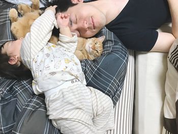 High angle view of family with cat sleeping on bed