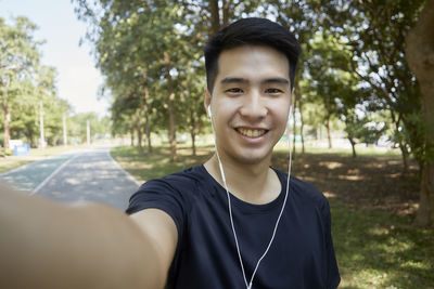 Portrait of smiling young man against trees