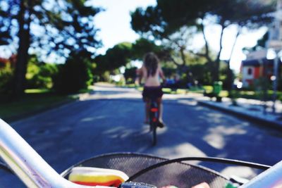 Rear view of woman with bicycle on road