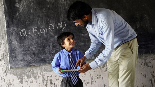 Side view of young man standing against wall