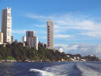 Buildings by sea against sky in city