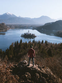 Rear view of man standing on cliff against sky