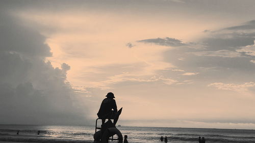 Silhouette man standing on beach against sky during sunset