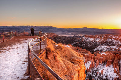 Rear view of friends standing at observation point against landscape during winter