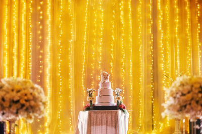 Layered cake on table against illuminated curtain