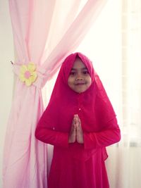 Portrait of girl standing against pink curtain