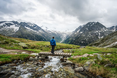 Man hiker resting on small bridge over mountaian river at schlegeis lake, zillertal alps, austria