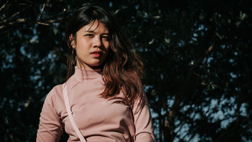 Portrait of beautiful woman standing against trees