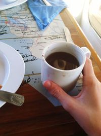 Close-up of hand holding coffee cup on table