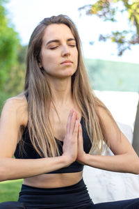 Portrait of young beautiful blonde woman practising yoga in the garden in a healthy lifestyle