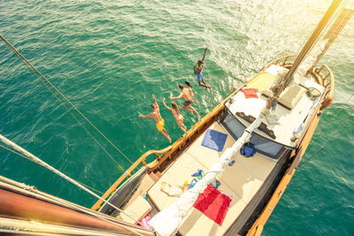 High angle view of friends jumping from boat in sea