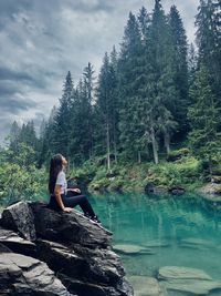 Man sitting on rock against trees in forest