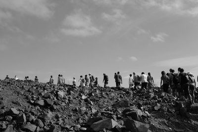 Low angle view of people walking on field against sky