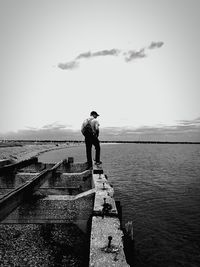 Man standing on rock by sea against clear sky