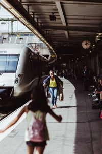 Woman with luggage running towards daughter at railroad station