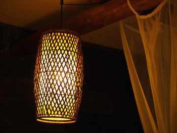 Low angle view of illuminated light bulb hanging from ceiling