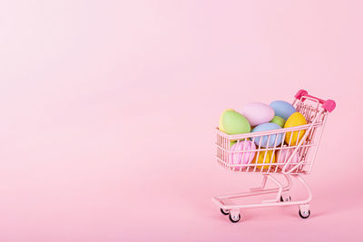 Close-up of miniature shopping cart against pink background