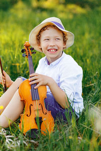 Portrait of cute curly boy young violinist  playing in violin on field