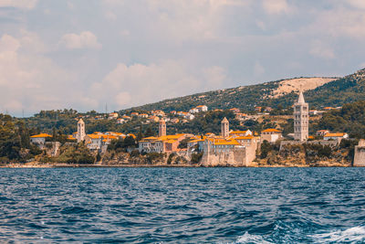 Sea by buildings against sky in city