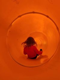 Rear view of woman sitting in orange