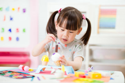 Young girl decorating hand made craft for homeschooling