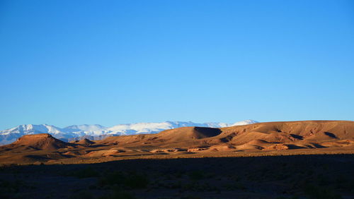 Scenic view of arid landscape against clear blue sky