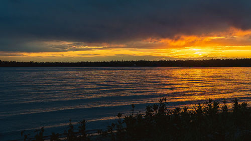 Scenic view of sea against dramatic sky during sunset