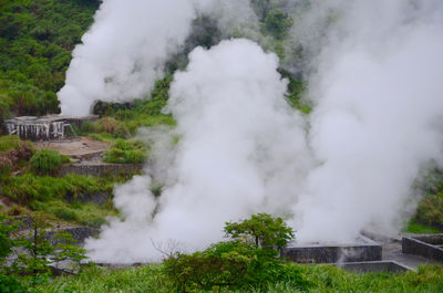 Smoke emitting from volcanic landscape against sky