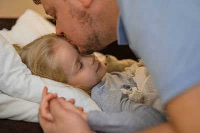 Dad kisses his sick child on the forehead before bed. father with tenderness and care kisses his