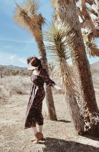 Girl in hat and dress dances near joshua trees