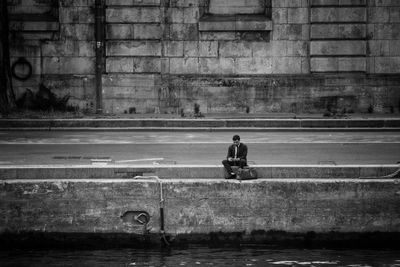 Man sitting on wall in city