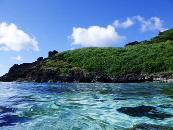 Scenic view of rocks by sea against sky