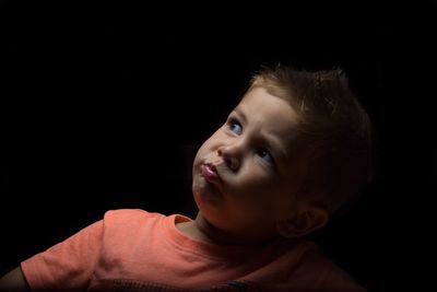 Portrait of cute boy against black background