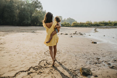 Rear view of mother and daughter on beach