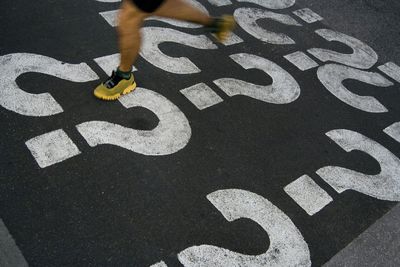 Low section of person running on street with question mark icons