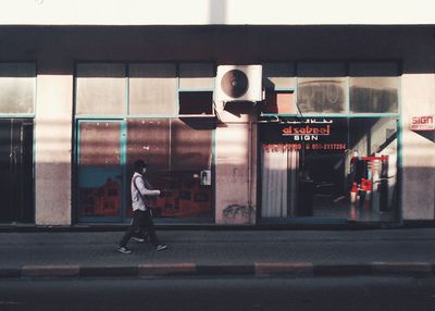 Rear view of man walking on road in city