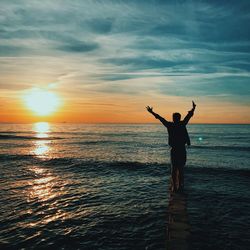 Silhouette man standing at beach against sky during sunset